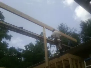 Carpenter setting a ridge beam over a new addition frame — Ice Dam Removal by Roofing Brothers in Ellenton