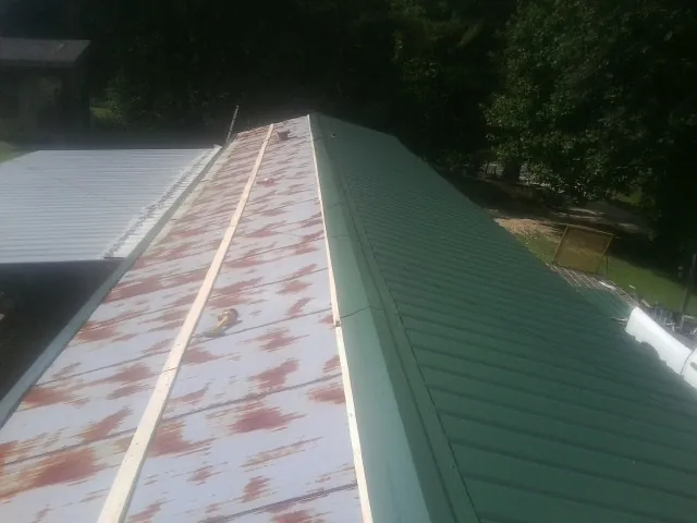 Old rusted panels beside newly installed green metal roofing — Wind Damage Roof Repair by Roofing Brothers in Ellenton