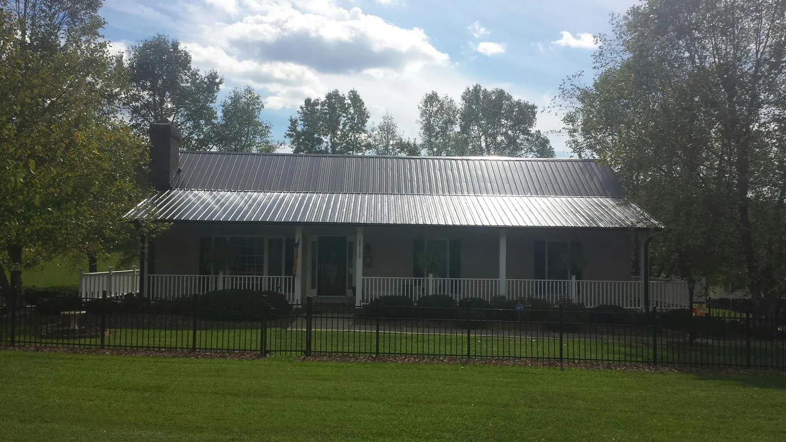Gray metal roof on a brick ranch with a full width front porch — Gutter Guard Installation work by our crew in Ellenton