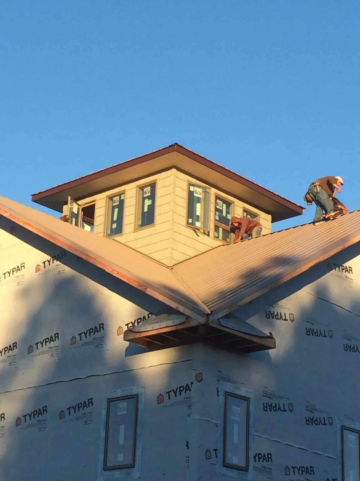 Roofers working around a rooftop cupola on a new metal roof at sunset — Roof Waterproofing in Ellenton by Roofing Brothers